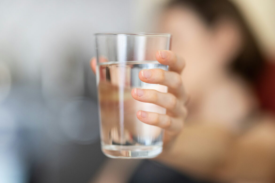 Trinken ist wichtig: Glas Wasser wird in der Hand gehalten.